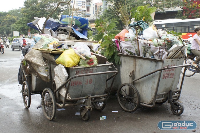 Hiện tượng tiện đâu để đó rồi mới kéo đi một thể của công nhân gom rác đã trở nên phổ biến trên nhiều tuyến phố Hà Nội. Ảnh: Tùng Dương.
