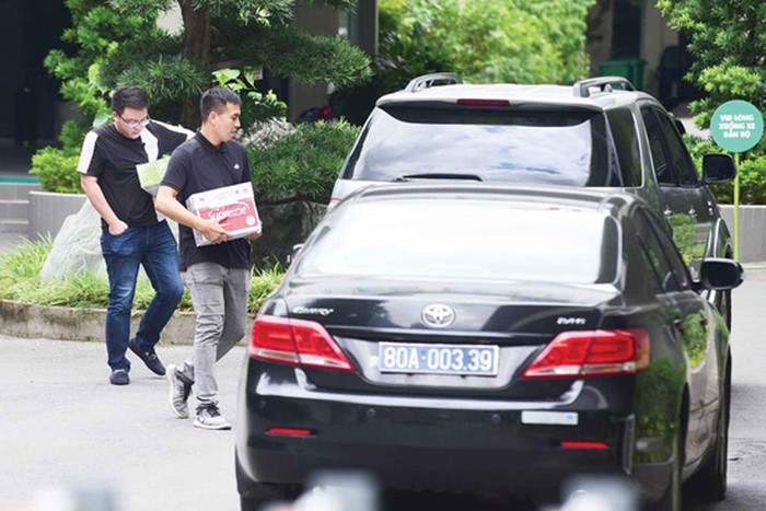 Lực lượng chức năng mang theo thùng giấy đựng các tài liệu thu giữ được tại Tổng công ty Nông nghiệp Sài Gòn trên đường Điện Biên Phủ, quận Bình Thạnh, Thành phố Hồ Chí Minh - Ảnh: Quang Định.