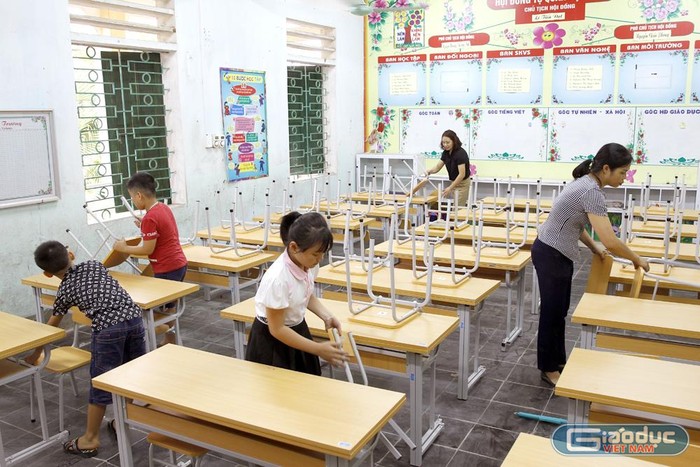 Các em học sinh Trường Tiểu học Lê Đồng đang sắp xếp lại những bộ bàn ghế mới. Ảnh: Tùng Dương.