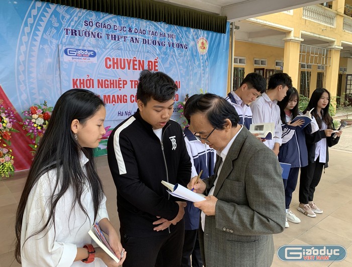 Giáo sư Nguyễn Lân Dũng tặng sách cho đại diện các em học sinh Trường Trung học phổ thông An Dương Vương. Ảnh: Tùng Dương.