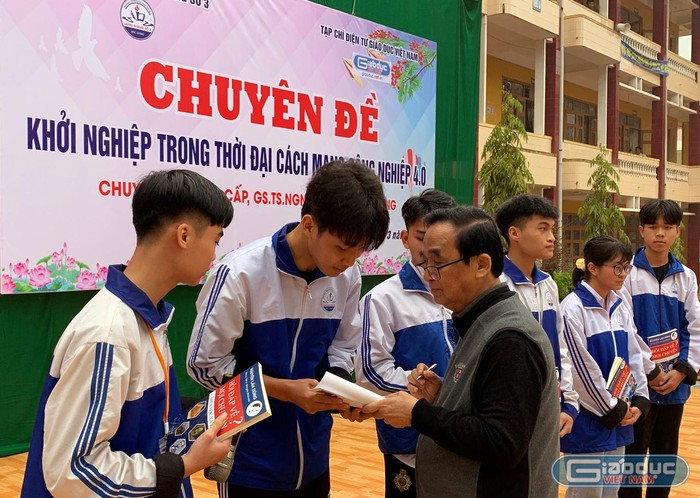 Giáo sư Nguyễn Lân Dũng ký tặng sách của mình cho học sinh Trường Trung học phổ thông Lạng Giang số 3. Ảnh: Tùng Dương.