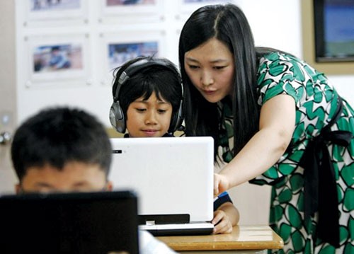 Giáo viên giúp HS học trên máy tính tại Trường tiểu học Sosu ở Gwesan (Hàn Quốc) - Ảnh: The Washington Post
