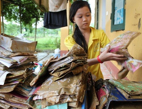 Em Lê Phương Anh (lớp 5A, Trường tiểu học Lương Sơn, Thường Xuân, Thanh Hóa) buồn rầu bên đống sách vở bị ướt, lấm lem bùn do mưa lũ.