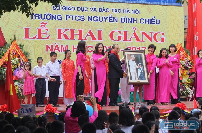 Thủ tướng trao tặng bức tranh Bác Hồ quàng khăn đỏ cho các em thiếu nhi, nhắc nhở về truyền thống hiếu học của dân tộc Việt Nam. ảnh: Ngọc Quang.