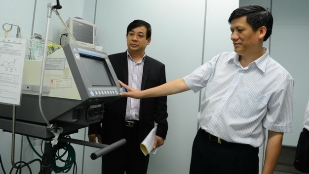 Thứ trưởng Bộ Y tế Nguyễn Thanh Long (phải) trong một lần kiểm tra thiết bị tại phòng cách ly đặc biệt ở Bệnh nhiệt đới TP.HCM Ảnh: Thuận Thắng/Tuổi trẻ.