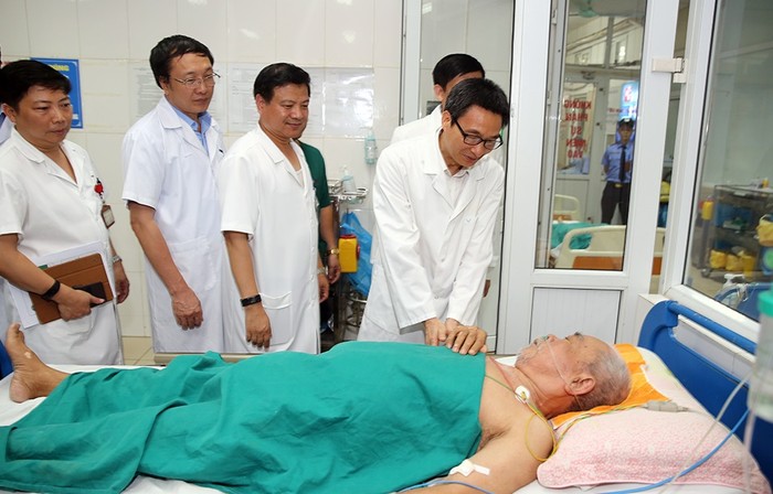 Phó Thủ tướng Vũ Đức Đam hỏi thăm một bệnh nhân cao tuổi mắc sốt xuất huyết đang điều trị tại Bệnh viện Nhiệt đới Trung ương. Ảnh: VGP/Đình Nam.