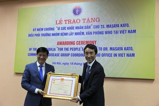 Thứ trưởng Bộ Y tế - ông Nguyễn Thanh Long trao kỷ niệm chương cho ông Masaya Kato (phải).