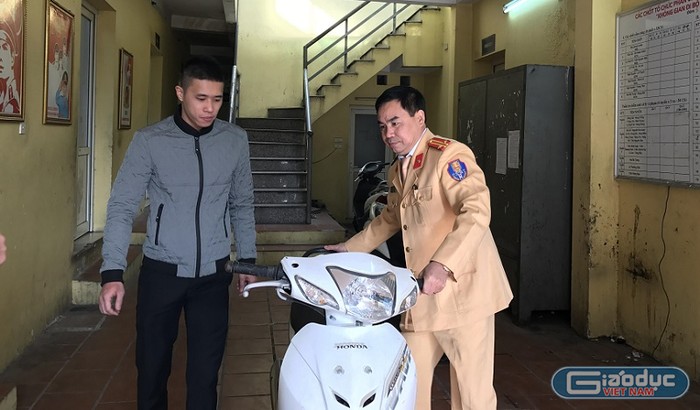 Trung tá Thiều Mạnh Ngọc dắt xe trao trả cho anh Nguyễn Đức Hiếu. ảnh: NQ.