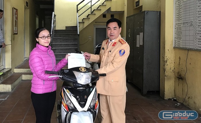 Trung tá Thiều Mạnh Ngọc trao trả xe cho chị Phạm Thị Lệ Hằng. ảnh: NQ.