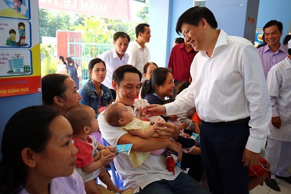 Ông Nguyễn Thanh Long trò chuyện với các bố mẹ đưa con đi tiêm chủng tại Trạm y tế xã Nghĩa Dõng, Quảng Ngãi. Ảnh: BS. Phạm Quang Thái