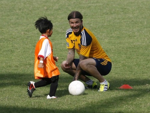 Beckham hí hửng dụ một em bé... đá bóng