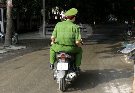 Một trong hai người mặc cảnh phục không đội mũ bảo hiểm khi ngồi trên xe máy.