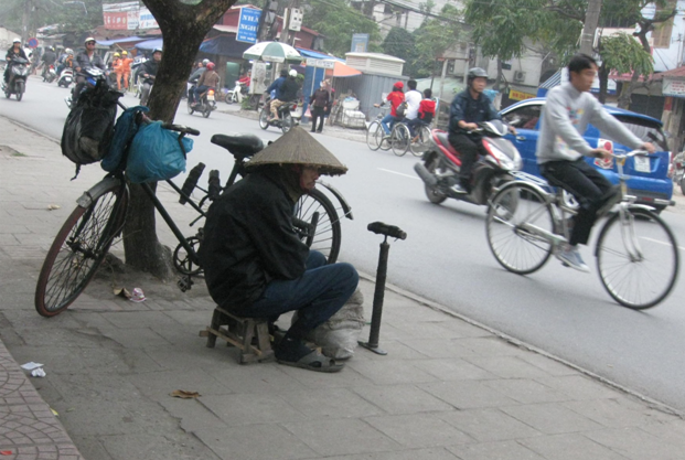 Ông lão sửa xe gần trạm xe bus bệnh viện Thanh Nhàn. (Ảnh: Đàm Thị Thùy)