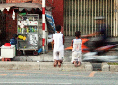 Hai đứa trẻ bị mẹ bắt quỳ gối trên dải phân cách đại lộ Đông Tây (TP. HCM).