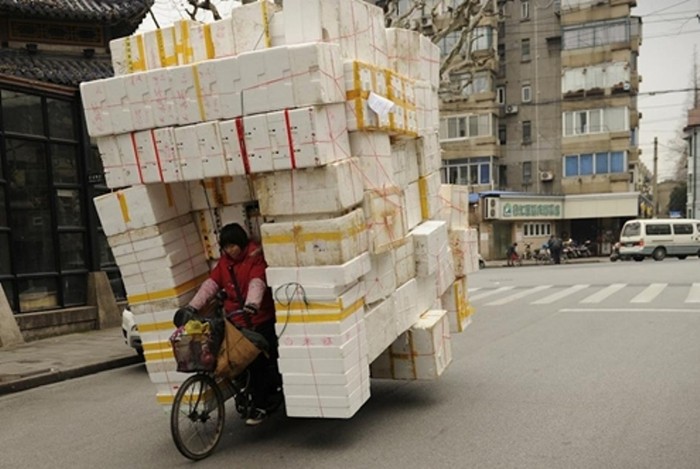 Một phụ nữ đạp xe chở đầy thùng xốp trên đường phố Thượng Hải (Trung Quốc). Kinh tế Trung Quốc đã tăng trưởng ì ạch suốt 7 quý qua khi cả nhu cầu nội địa và quốc tế, đặc biệt từ Âu - Mỹ, giảm sút. (Ảnh: AFP)