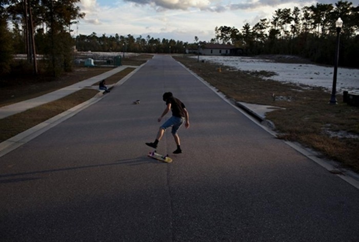 Một em bé trượt ván trên con đường vắng vẻ tại dự án nhà dang dở có tên Enclave ở DeLand, bang Florida (Mỹ) ngày 24/1. DeLand thuộc Hạt Volusia, một trong những nơi có tỷ lệ bị thu hồi nhà thế chấp lớn nhất bang Florida. (Ảnh: Wall Street Journal)