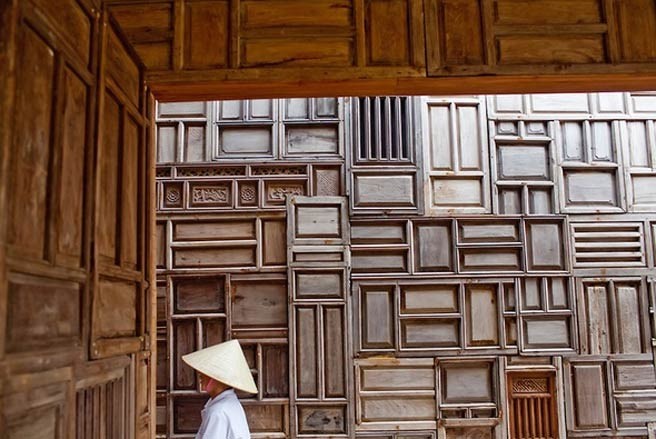 Six Senses Côn Đảo được ví như một bức tranh với sự phối màu nghệ thuật. Trong ảnh là một phụ nữ đứng trước bức tường được làm từ rất nhiều cánh cửa gỗ ghép lại - Ảnh: Justin Mott.