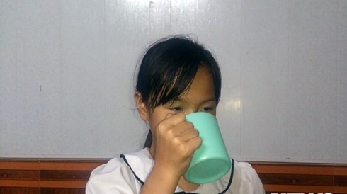 Bé Phương Anh cầm cái cốc ở nhà mô tả lại cái cốc tương tự em đã từng uống 1/2 nước giặt giẻ lau bảng ở lớp do cô giáo phạt.