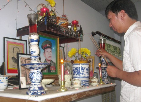 Anh Minh, anh trai Phước, thắp nhang lên bàn thờ báo công với người cha đã khuất.