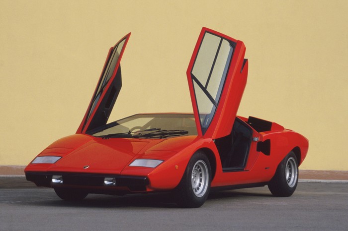 2. Lamborghini Countach (1974 - 1990) Countach là mẫu xe thể thao động cơ đặt giữa được Lamborghini đưa vào sản xuất trong khoảng thời gian từ năm 1974 đến 1990. Đây có thể xem là mẫu xe tiên phong và định hình phong cách hầm hố, góc cạnh của các dòng xe Lamborghini nói riêng và siêu xe nói chung. Thiết kế đẩy cabin lái về phía trước nhằm tăng diện tích cho động cơ, và đặc biệt là cửa ra vào đóng mở kiểu cắt kéo cũng từ chính Countach mà ra. Cái tên Countach bản thân nó cũng có một "tiểu sử" thú vị riêng. Đây là một từ cảm thán trong ngôn ngữ địa phương tại Ý có tên Piedmontese, thường được sử dụng bởi nam giới mỗi khi nhìn thấy một người phụ nữ tuyệt đẹp. Những lô Countach đầu tiên sử dụng chung động cơ V12 4 lít của Miura, sau này được nâng cấp lần lượt lên 5 lít rồi 5,2 lít. Có cả thảy 5 phiên bản Countach được sản xuất, bao gồm LP400, LP400S, LP500S, LP5000QV và một phiên bản đặc biệt nhân kỷ niệm 25 năm Countach ra đời. Tổng cộng, Lamborghini đã chế tạo được 2.042 chiếc Countach trong vòng đời 16 năm của nó. Cái tên Countach chỉ bị lu mờ phần nào kể từ khi kẻ kế nhiệm nó xuất hiện, Lamborghini Diablo.