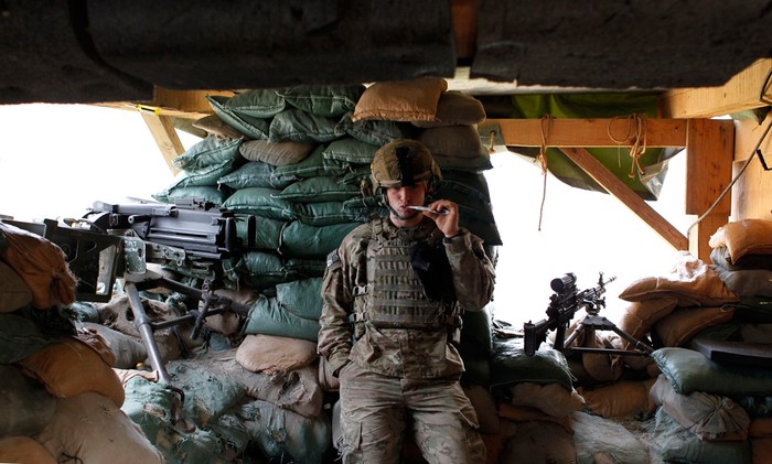 Một người lính thuộc lực lượng Task Force “No Fear” đứng đánh răng giữa 2 khẩu súng máy trong một boongke ở tiền đồn Bari Alai.