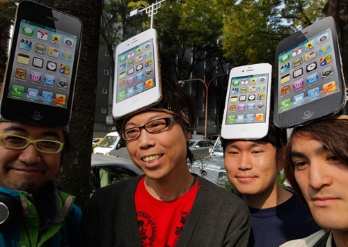 Các iFan Nhật Bản ở Tokyo sáng tạo những chiếc mũ đội đầu là iPhone 4S trong lúc chờ đến lượt mua hàng (Ảnh: AP)