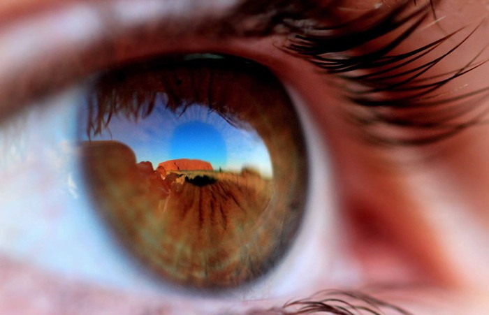 Bức ảnh của tác giả Robert Spanring. Có rất nhiều người hành hương về ngọn núi Uluru, Australia, nhưng những gì mà họ nhìn thấy trong mắt phụ thuộc từ nơi họ đến. Uluru là một ngọn núi đá khổng lồ màu cam nâu, có hình hình bầu dục, hình thành từ 680 triệu năm trước đây, không chỉ là biểu tượng ở Australia mà còn là điểm du lịch hấp dẫn của thế giới. Nhìn từ xa, Uluru giống như một hòn đảo nổi lên giữa sa mạc bao la, nóng rát với nhiệt độ lên đến 40 độ C. Điều đặc biệt là từ sáng đến khi trời chạng vạng, màu sắc của ánh sáng thay đổi nhiều lần trên vách núi Uluru từ màu đỏ nhạt chuyển sang màu cam và đỏ thẫm, nâu vàng. Khi trời mưa to hoặc mưa vừa tạnh, ngọn núi lại nhuốm màu tro bạc, pha lẫn chút đen. Các nhà khoa học cho rằng, nguyên nhân đổi màu của Uluru là do đặc tính của núi đá. Đây là một khối đá ráp thạch anh, chất đá cứng rắn, kết cấu chặt chẽ. Bề ngoài của đá ráp màu đỏ có chất oxy sắt, khi ánh nắng mặt trời chiếu vào dưới nhiều góc độ khác nhau sẽ đổi màu liên tục. Uluru mang ý nghĩa tinh thần đáng kể đối với thổ dân trong vùng. Ở chân núi có một thông báo lớn yêu cầu mọi người không được leo lên ngọn núi thánh bởi tín ngưỡng và sự an toàn cho du khách. Uluru đã được UNESCO công nhận là một trong bảy kỳ quan thiên nhiên thế giới và đã được quy hoạch thành công viên quốc gia, hàng năm thu hút hàng nghìn lượt du khách tham quan.