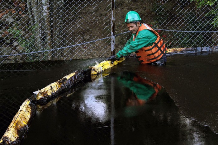 32. Một nhân viên đứng bên cạnh hàng rào sau vụ tràn dầu từ Caño Limón-Coveñas, thuộc Chinacota, Clombia ( 11/12/2011). Vụ tràn dầu này đã gây ảnh hưởng đến nguồn nước của thành phố Cucuta.
