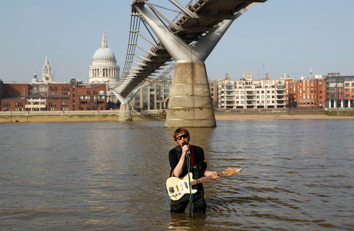 33. Người hát rong chơi đàn ghi ta điện trên dòng sông Thame khi thủy triều lênb tại London ( 15/ 3/ 2012 ).