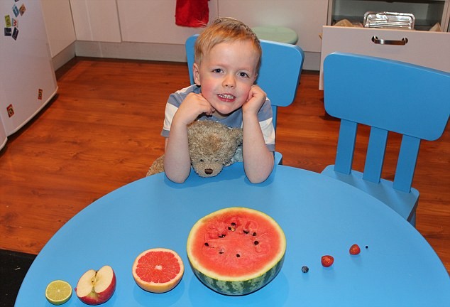 Cậu bé Jame bên cạnh các hành tinh được tạo thành từ trái cây tươi trong bức hình dự thi của Ruth Mc Lernon