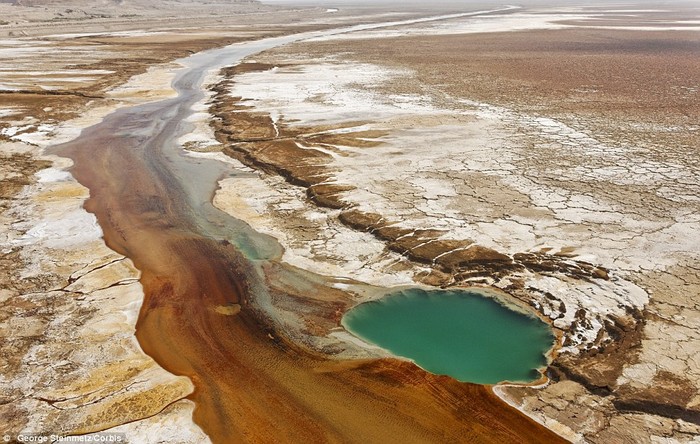 19. Nước muối thấm ra khỏi mặt đất và tạo thành dòng sông màu nâu di chuyển về phía Bắc của một hồ thuộc Biển Chết.