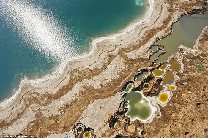 24. Các hố sụt giống như những nốt mụn đậu mùa nổi lên trên bờ Biển Chết gần Ein Gedi, Israel. Các hố sụt này được gây ra do mạch nước ngầm hòa tan vào muối dưới đáy Biển Chết.