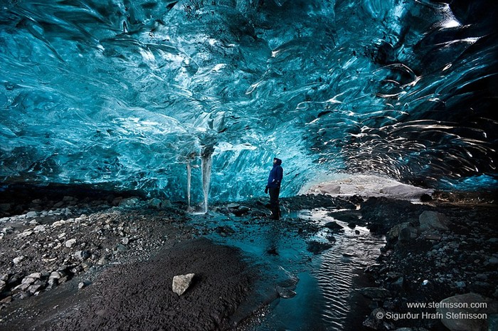 Nhiếp ảnh gia Sigurður đứng bên trong hang động băng ở sông băng Vatnajokull. Thông thường các hang động băng đều khá tối tuy nhiên một vài hang lại có vòm mái mỏng đủ để ánh sáng xuyên vào.