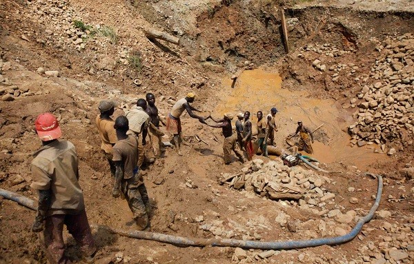 Những chiếc thau chất nặng bùn được chuyền tay qua tay những người đàn ông lên đến đỉnh núi. Ở đây, bùn sẽ được lọc ra để tìm kiếm những hạt vàng nhỏ bé. Hầu hết, vàng và kim cương ở thị trấn Mongbwalu, Congo này có được bằng chính sự bóc lột sức lao động của những người thợ mỏ. (Ảnh: Jonny Hogg).