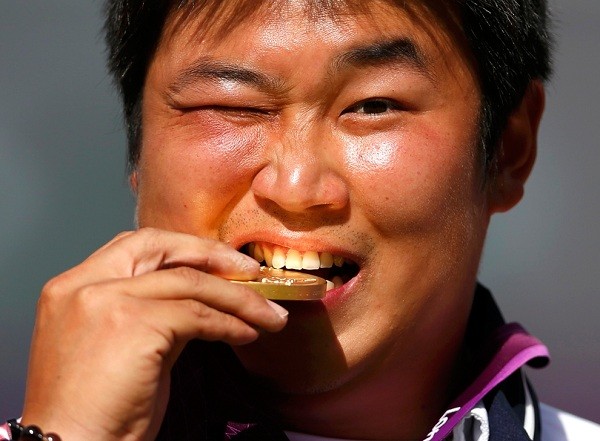 Chàng trai Hàn Quốc - Oh Jin Hyek rất vui sướng, hạnh phúc và cắn tấm huy chương vàng của mình trong buổi lễ trao giải bắn cung cá nhân tại Thế vận hội Olympic London 2012 ở Lord’s Cricket Ground. (Ảnh: Suhaib Salem).