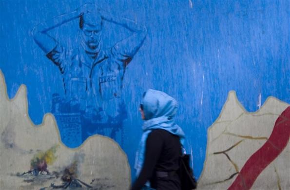 Một phụ nữ đang đi qua bức tường có hình ảnh của một con tin người Mỹ bên ngoài đại sứ quán Mỹ trước đây tại Tehran.