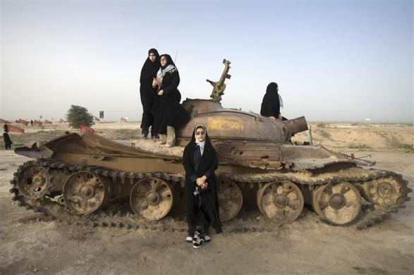 Phụ nữ Iran đứng bên cạnh một chiếc xe tăng của Iraq đã bị bỏ lại sau cuộc chiến tranh. Nơi này đã thành một địa điểm tưởng niệm chiến tranh gần biên giới Iraq, ở tỉnh Khoozestan.