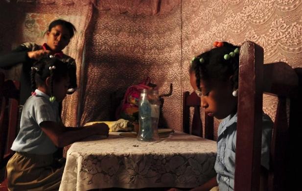 Một người mẹ đang chải tóc cho các cô con gái chuẩn bị đến trường ở Santo Domingo, Cộng hòa Dominica.