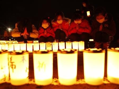 Các bé gái cầu nguyện sau khi thắp sáng những ngọn nến tại một lễ kỷ niệm ở Iwaki, Fukushima ngày 10/3/ 2012.
