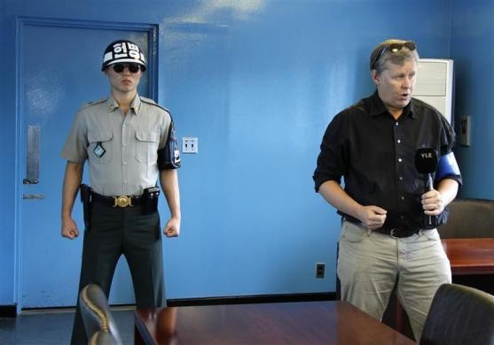Nam phóng viên đến đưa tin và bên cạnh là một người lính Hàn Quốc canh gác tại khu phi quân sự.