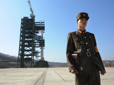 Một người lính Triều Tiên đang đứng gác gần tên lửa Unha-3.