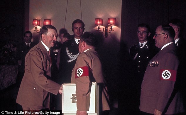 Hitler bắt tay với nhiếp ảnh gia của ông, Heinrich Hoffmann. Bác sĩ riêng của Hitler, Giáo sư Theodor Morell đứng ở bên phải trong tấm hình.