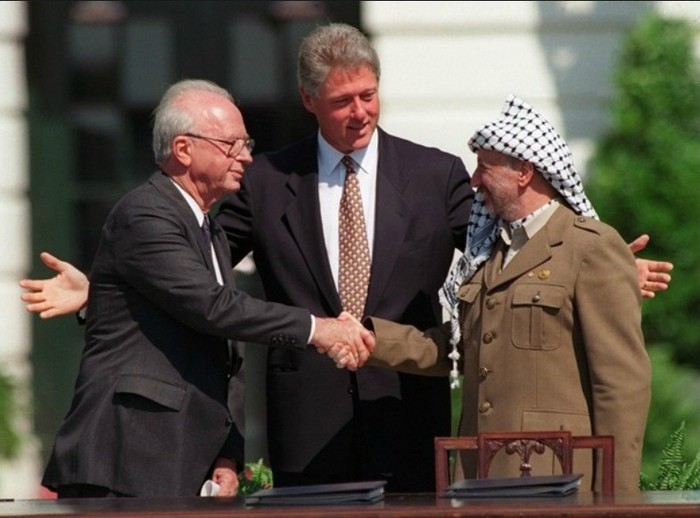 Thủ tướng Israel - Yitzhak Rabin (trái) và Yasser Arafat, nhà lãnh đạo của Tổ chức Giải phóng Palestine, bắt tay trước một đám đông trên bãi cỏ Nhà Trắng vào ngày 13/9/1993. Đây là cái bắt tay đầu tiên trước công chúng của hai nhà lãnh đạo trong các cuộc đàm phán hòa bình giữa Israel và các vùng lãnh thổ Palestine. Mặc dù tương đối lạc quan, thỏa thuận đã không bao giờ trở thành hiện thực.