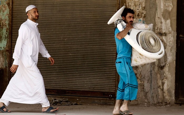 Một người đàn ông đang mang theo chiếc quạt khi chạy trốn khỏi Aleppo.