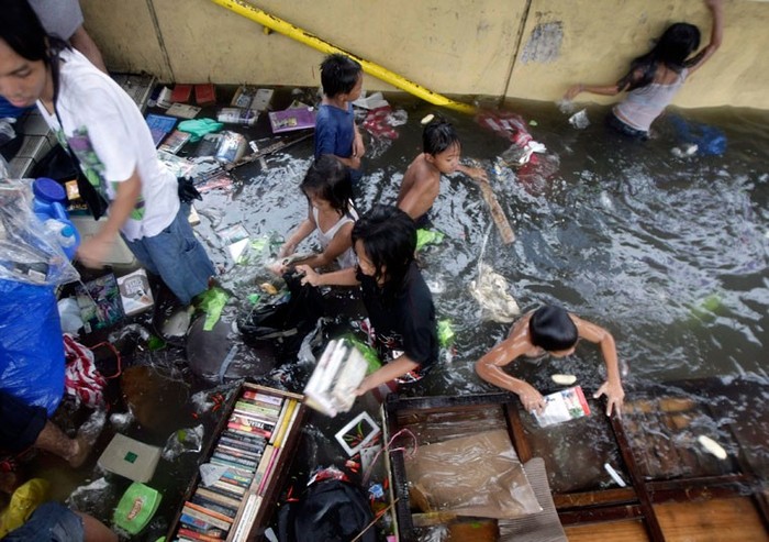 Người dân đang cố gắng vớt sách và DVD tại một đường hầm cho người đi bộ bị ngập lụt ở Manila.