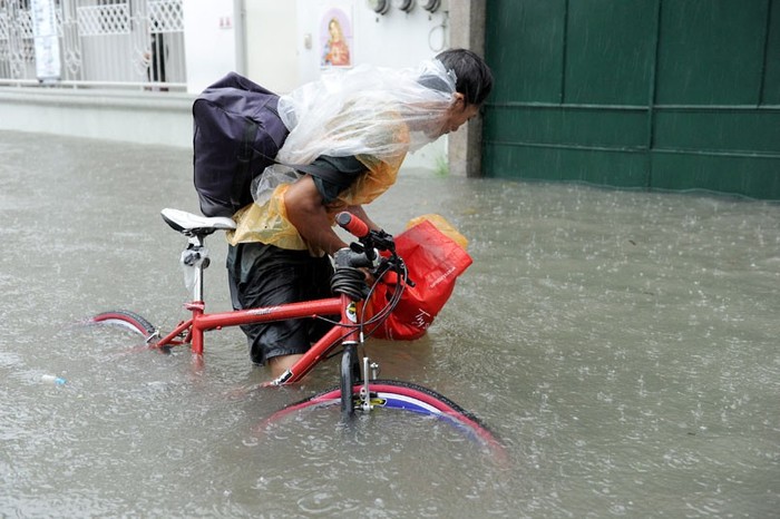 Một người dân đang cố đẩy chiếc xe đạp ra khỏi dòng nước.