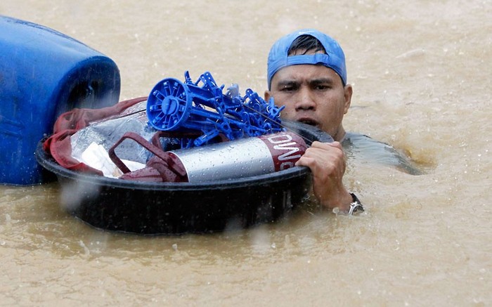 Một người đàn ông mang theo đồ đạc của mình trong khi lội qua một con đường ngập nước ở thành phố Marikina.