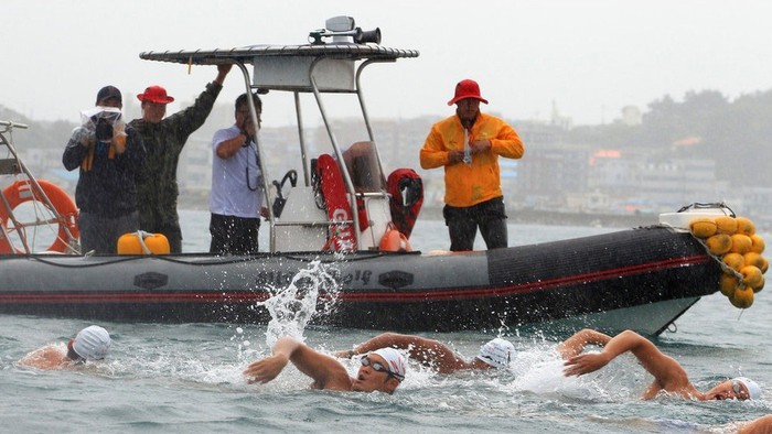 Thuyền cứu hộ đi bên cạnh đội bơi lội.