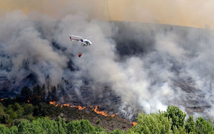 Một máy bay trực thăng chữa cháy chuẩn bị phun nước chữa cháy rừng trên một sườn đồi gần ngôi làng ở Galicia, tây bắc Tây Ban Nha.