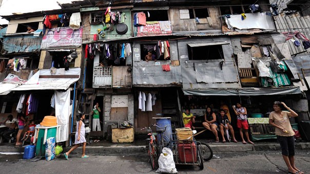 Nhiều người dân ngồi bên ngoài một dãy khu nhà lụp xụp, tồi tàn ở quận tài chính của Manila.